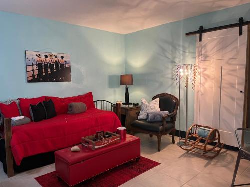 a living room with a red bed and a chair at Blue Bell Apartment Hotel in Fort Lauderdale