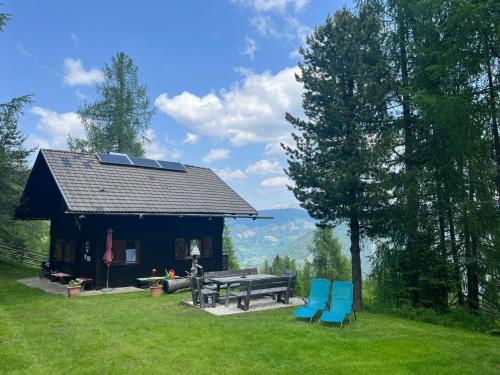 a log cabin with a picnic table and blue chairs at Neuwirth Hütte in Gnesau