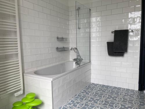 a white bathroom with a tub and a shower at Maison MOKASSI in Laloubère