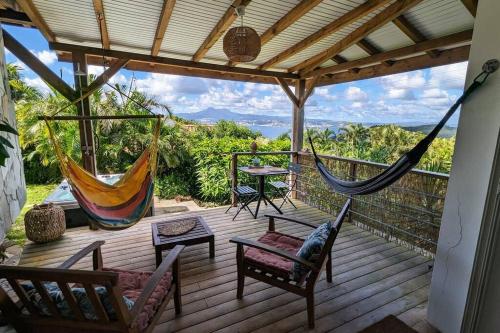 een veranda met een hangmat en een tafel en stoelen bij Cocon de charme avec spa, proche de la plage in Les Trois-Îlets