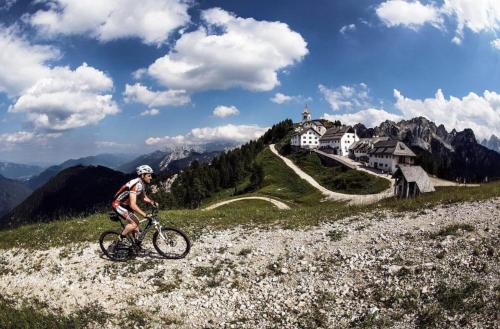 a man riding a bike on a hill with a house at Villa Verde - Cave del Predil in Cave del Predil