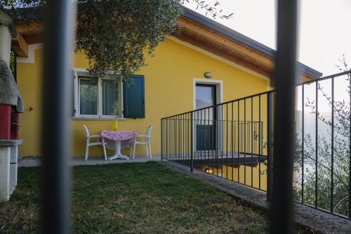 a yellow house with a table and chairs in a yard at CASA NAVLA' AppartamentI "Ulivi"- "Fiori" -"Velieri"-"Luna"-"Nido"-"Taverna" in Tignale