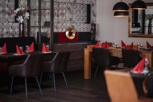 a restaurant with tables and chairs with red napkins on them at Hotel Lindenhof in Erkelenz