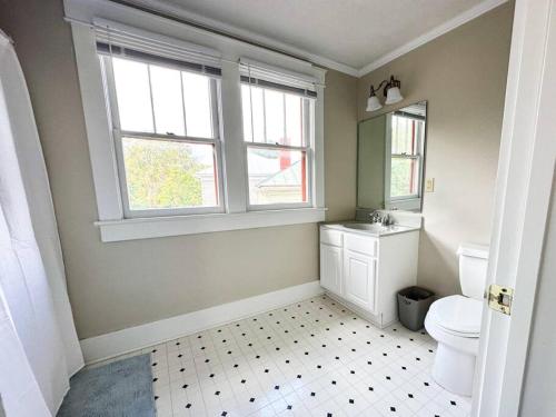 a bathroom with a toilet and a sink and two windows at Spacious Craftsman near Staunton in Staunton