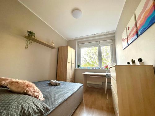 a bedroom with a bed and a desk and a window at MMRent Desert Room in Gdańsk
