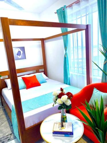Un dormitorio con una cama y una mesa con un jarrón de flores en Pilipili Kijani Luxury homes en Mombasa