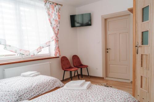1 dormitorio con 2 camas, ventana y 2 sillas en U Progu Lasu en Orzeszkowo