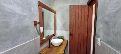 ein Badezimmer mit einem Spiegel und einer Schüssel auf einem Holztisch in der Unterkunft Sítio Roda d'Água in Lagoa Santa