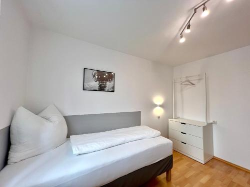 a bedroom with a white bed and a white dresser at Stadthaus 1911 in Bludenz