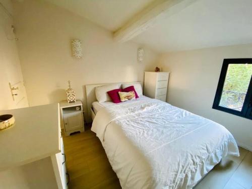 ein Schlafzimmer mit einem weißen Bett mit rosa Kissen in der Unterkunft La Saline in Aigues-Mortes
