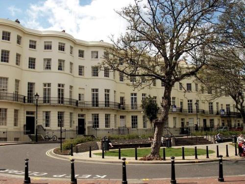 a large white building with a tree in front of it at Stunning town centre apartment with sea views in Worthing