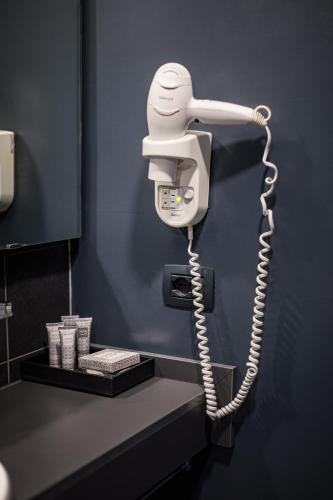a white phone hanging on a wall in a bathroom at NEW IPOINT HOTEL in San Giovanni in Persiceto