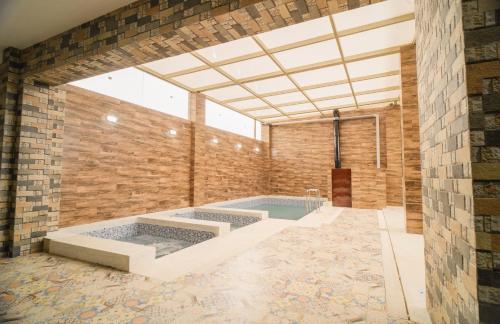 um quarto amplo com uma piscina e uma parede de tijolos em Suite Spa Puñuykuna em Cajamarca