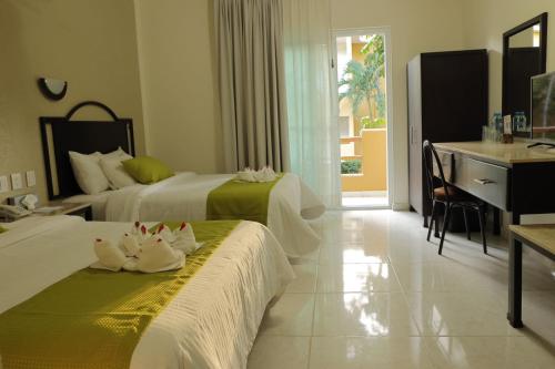 a hotel room with two beds and a desk at Hotel Chablis Palenque in Palenque