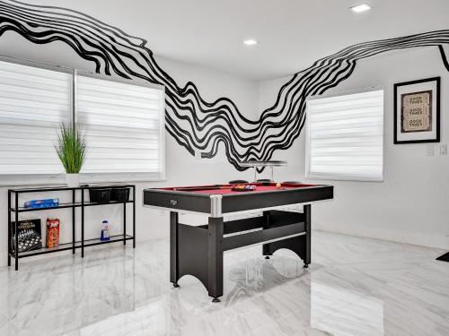 a ping pong table in a room with a wall with a painting at Chic Miami Escape- 4 Bedrooms, Game Room, Fire Pit, Pergola in North Miami Beach