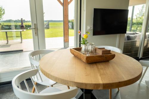 a wooden table with white chairs and a television at Vakantieverblijf Weidezicht in Dorst