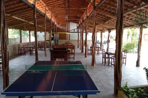 - une table de ping-pong dans un pavillon avec des tables et des chaises dans l'établissement Chalé em Barreirinhas - MA, à Barreirinhas