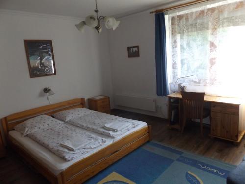 a bedroom with a bed and a desk and a window at Almafás Jakuzzis Vendégház Őrség in Kerkakutas