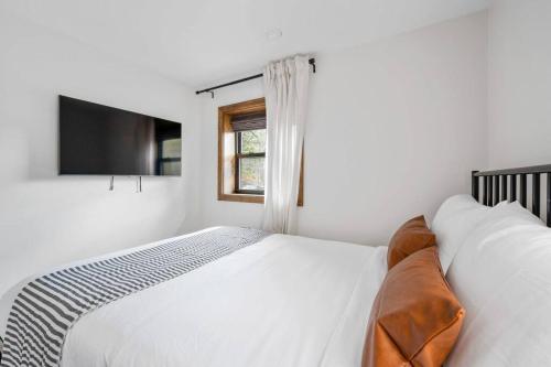 a white bedroom with a bed and a television at Chateau Bungalow - Ski Belleayre, Hunter in Shandaken