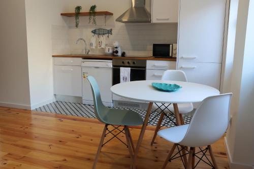 a kitchen with a white table and four chairs at Alojamento da Joana in Aveiro