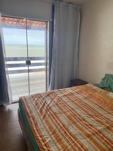 um quarto com uma cama e uma grande janela em Casa de Praia PÉ NA AREIA em Rio das Ostras RJ em Rio das Ostras