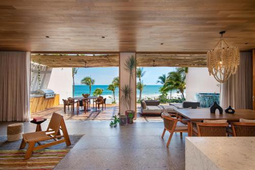 una sala de estar abierta con mesa, sillas y el océano en W Punta de Mita en Punta Mita