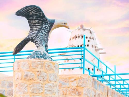 a statue of a bird sitting on a wall with a lighthouse at Al Burj Hotel in Tunis