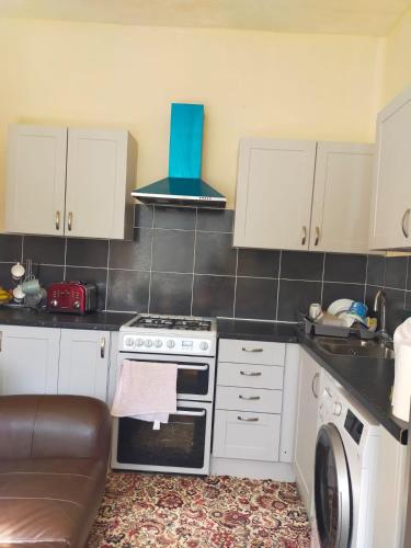 cocina con armarios blancos, fogones y lavavajillas en Female Only Room, en Bradford