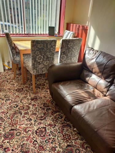 sala de estar con sofá de cuero, mesa y sillas en Female Only Room, en Bradford