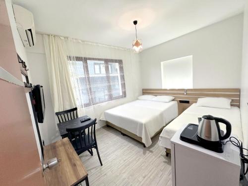 a hotel room with two beds and a table and a kitchen at Menesa Hotel in Istanbul