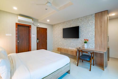 a bedroom with a bed and a desk and a tv at Harvey's Hotels (Gachibowli) in Hyderabad