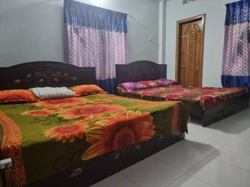 a bedroom with two beds with flowers on them at Syed monjil 