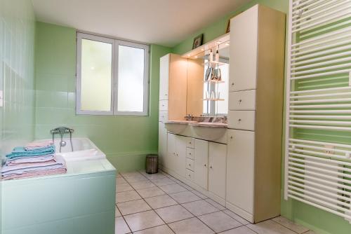 La salle de bains aux murs verts est pourvue d'un lavabo et d'une baignoire. dans l'établissement Le cèdre du Prieuré, à Montreuil-le-Henri