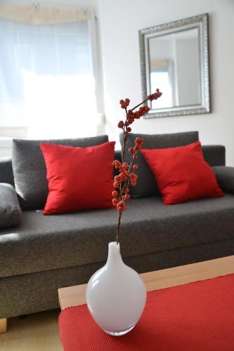 a white vase with a plant in it in front of a couch at Sonnenhaus Ferienwohnungen in Traben-Trarbach