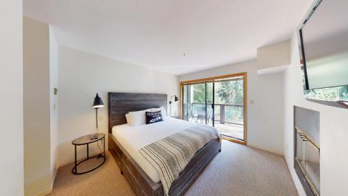 a white bedroom with a bed and a window at Powderhorn by Whistler Premier in Whistler