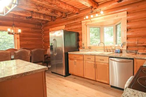 cocina con nevera de acero inoxidable y paredes de madera en Wilderness Vista Retreat, en Reed City