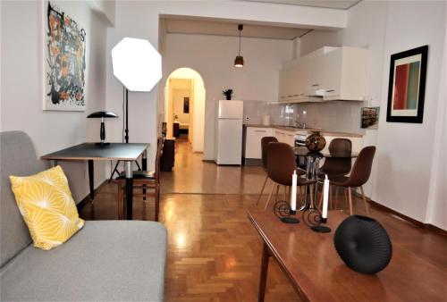 Cozy 2 Bedroom apt @Panormou Metro/Erytros Stavros في أثينا: غرفة معيشة ومطبخ مع طاولة وكراسي