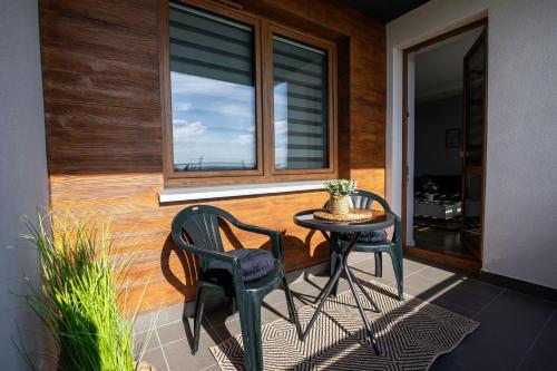 eine Terrasse mit einem Tisch, 2 Stühlen und einem Fenster in der Unterkunft VIP Apartamenty Lubelska II in Rzeszów