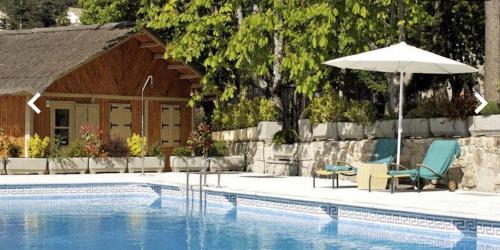 a swimming pool with two chairs and an umbrella at Palacio de Miraflores in Miraflores de la Sierra