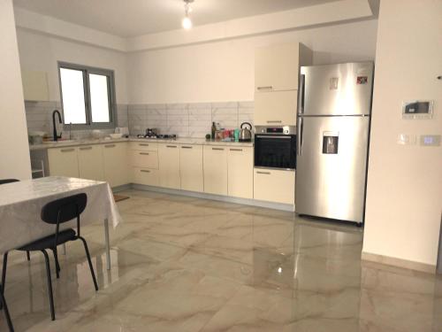 a kitchen with a stainless steel refrigerator and a table at Unique Luxurious New 4BR near Beach in Haifa