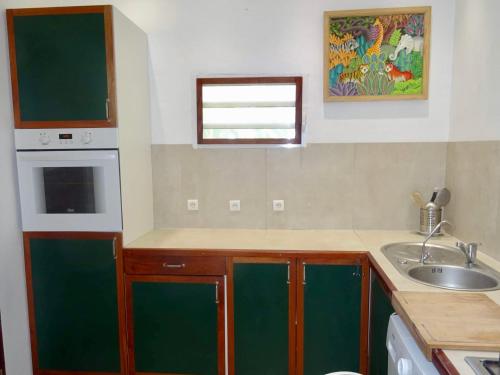 a small kitchen with a sink and a microwave at Bungalow DOUROU in Deshaies
