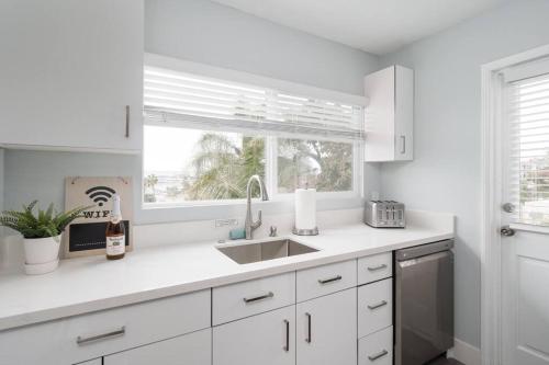 a white kitchen with a sink and a window at Bankers Hill Chic Roomy Home Near Airport in San Diego