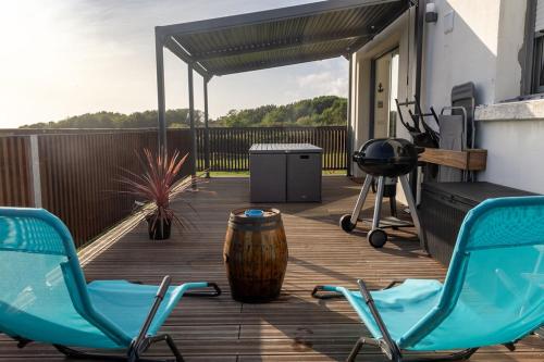 two chairs and a table on a deck at Appartement Nature et Mer. in Moëlan-sur-Mer