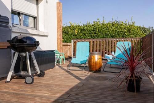 a patio with two chairs and a grill and a plant at Appartement Nature et Mer. in Moëlan-sur-Mer
