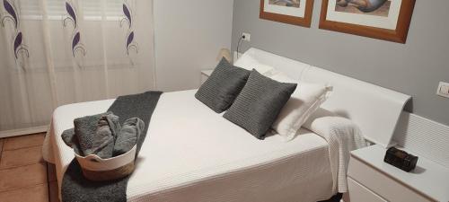 uma cama branca com almofadas pretas e brancas em Casa Rural La Tejeria 