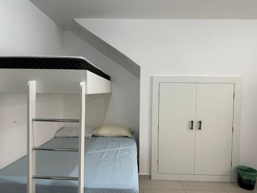 a white bedroom with a bunk bed and a closet at Apartamento studio térreo in Balneário Camboriú