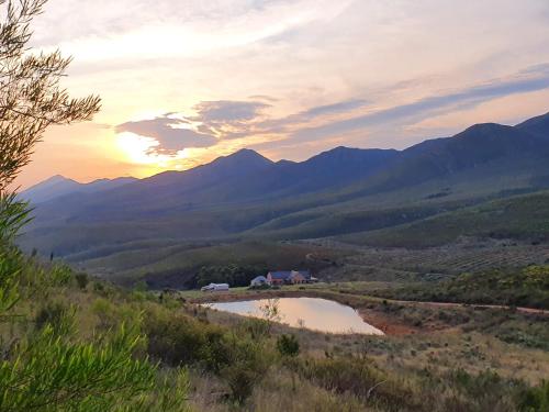 un tramonto su una valle con un lago e montagne di Helpmekaar Farm a Kareedouw