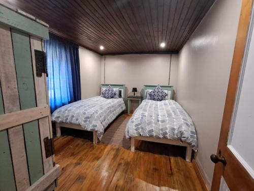 2 łóżka w pokoju z drewnianą podłogą w obiekcie Old Farmhouse Cottage w mieście Kareedouw