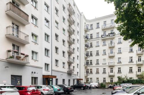 een groot wit gebouw met auto's geparkeerd op een parkeerplaats bij Apartament Paparazzi in Warschau