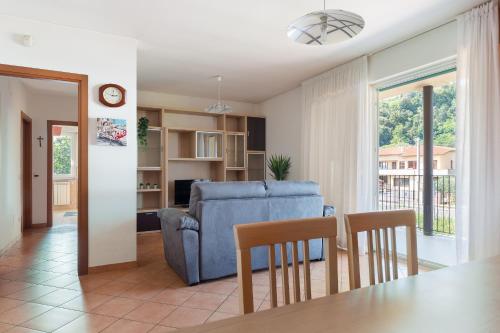 a living room with a blue couch and a table and chairs at Una Finestra Sulle Montagne in Albavilla